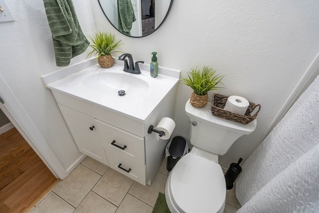 bathroom featuring tile patterned flooring, a textured wall, vanity, and toilet