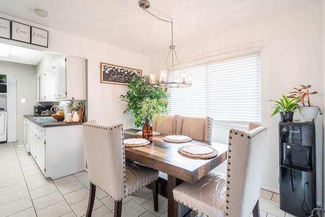 dining area with light tile patterned floors, washer / clothes dryer, and an inviting chandelier