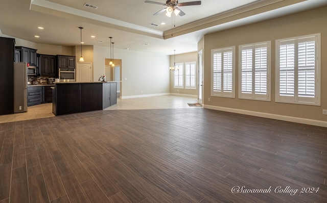 unfurnished living room featuring dark hardwood / wood-style floors, a raised ceiling, and ceiling fan with notable chandelier