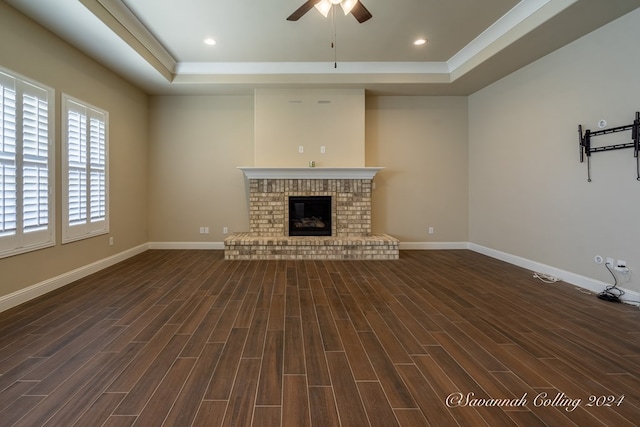 unfurnished living room featuring a tray ceiling, a fireplace, and dark hardwood / wood-style flooring