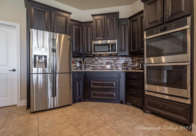 kitchen with dark brown cabinets, light stone counters, backsplash, and appliances with stainless steel finishes