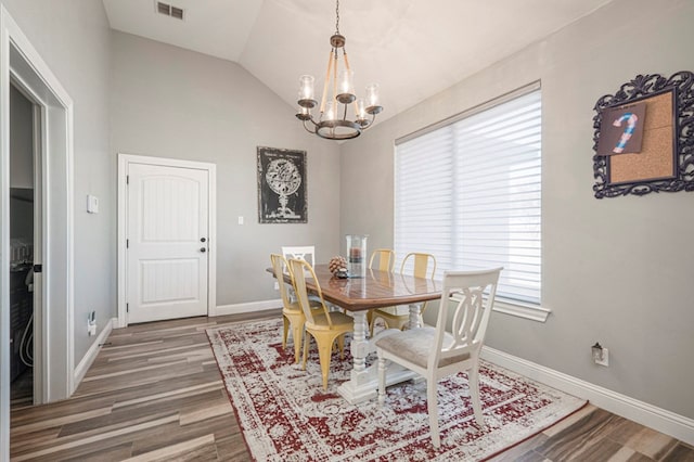 dining space featuring vaulted ceiling, dark wood-type flooring, and a chandelier