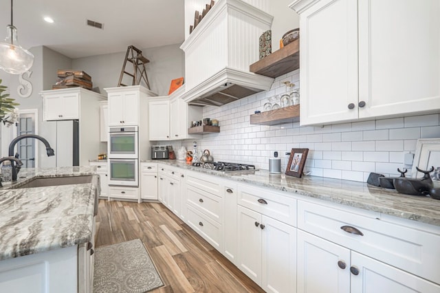 kitchen with hanging light fixtures, white cabinetry, appliances with stainless steel finishes, and tasteful backsplash