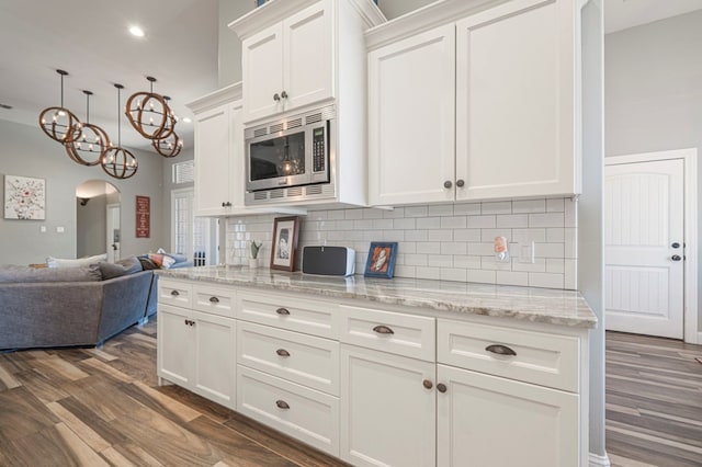 kitchen with stainless steel microwave, white cabinetry, tasteful backsplash, and dark hardwood / wood-style floors