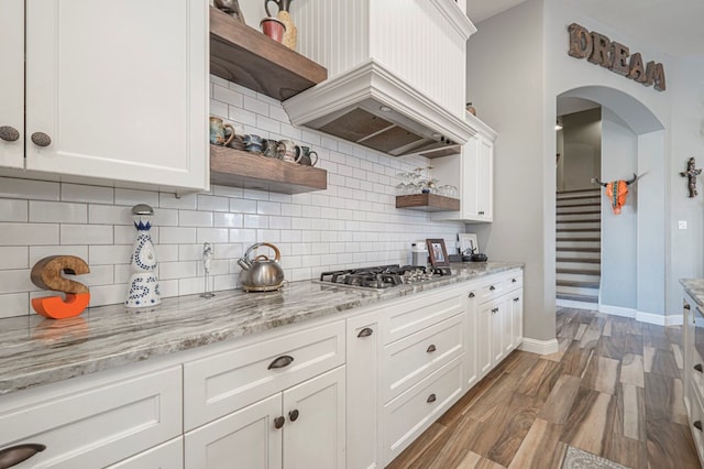 kitchen featuring white cabinetry, premium range hood, backsplash, and stainless steel gas cooktop