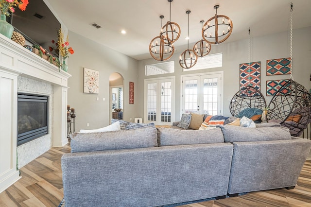 living room with a notable chandelier, light hardwood / wood-style flooring, and french doors