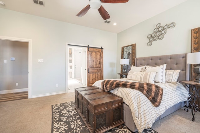 carpeted bedroom with ceiling fan and a barn door