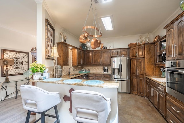 kitchen featuring a kitchen breakfast bar, decorative backsplash, appliances with stainless steel finishes, a peninsula, and ornamental molding
