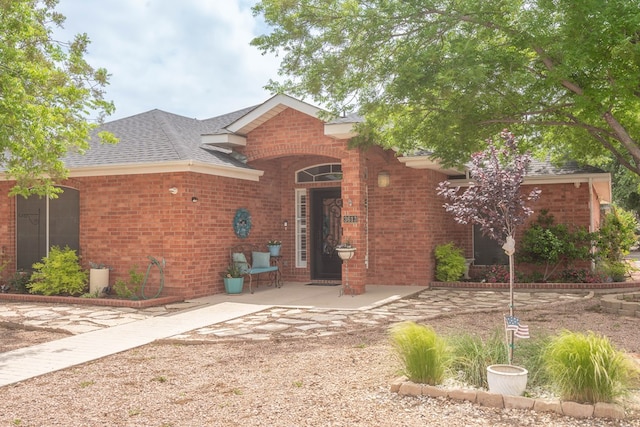 view of front of property with brick siding and roof with shingles