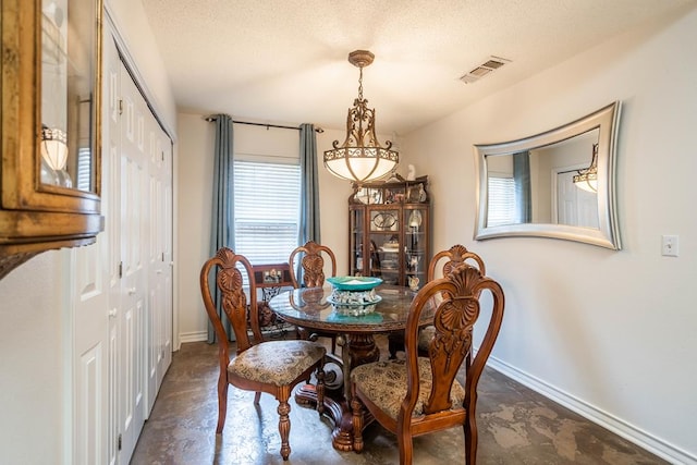 dining room featuring visible vents, baseboards, concrete floors, a textured ceiling, and a notable chandelier