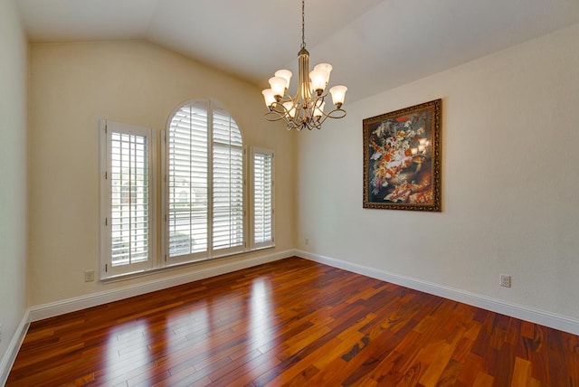 empty room featuring lofted ceiling, baseboards, and wood finished floors