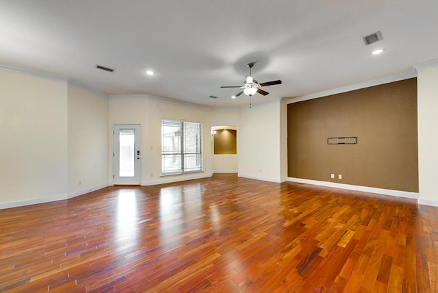 spare room with arched walkways, ceiling fan, wood finished floors, visible vents, and ornamental molding