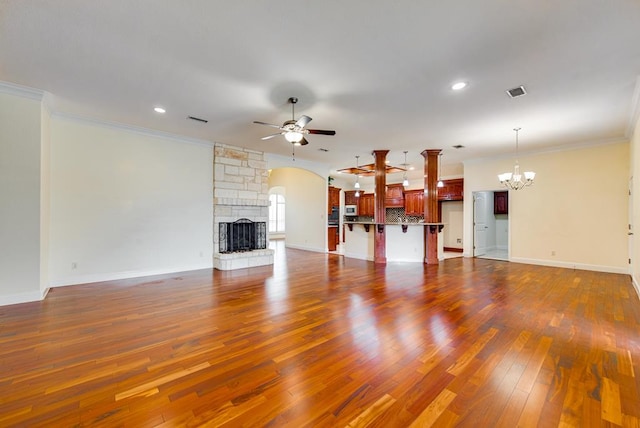 unfurnished living room featuring ceiling fan with notable chandelier, a fireplace, visible vents, and crown molding