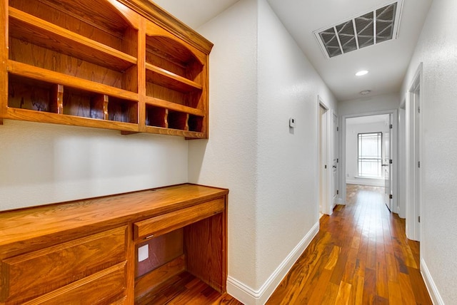 hall featuring baseboards, visible vents, and dark wood finished floors