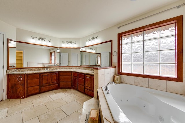 bathroom with a tub with jets, tile patterned flooring, vanity, and a wealth of natural light