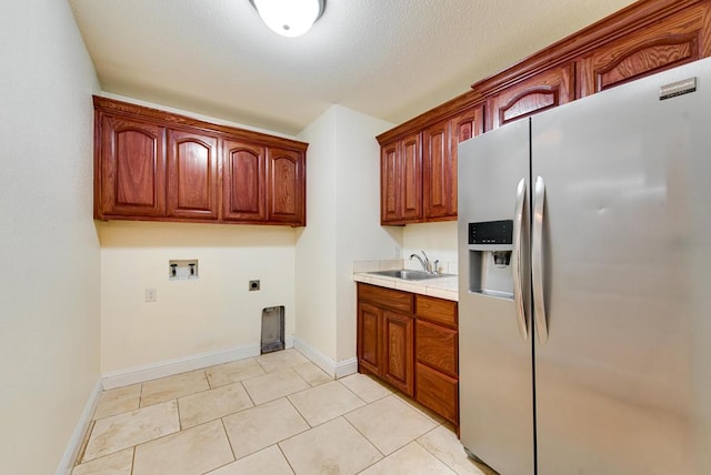 kitchen with baseboards, stainless steel refrigerator with ice dispenser, a sink, and light countertops