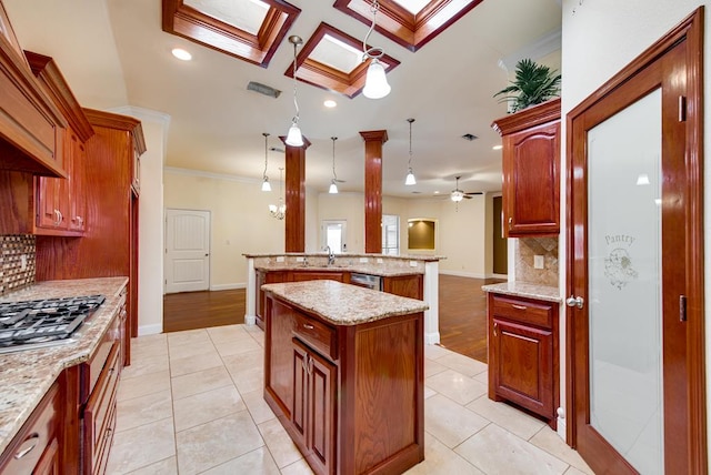 kitchen with light tile patterned floors, a kitchen island with sink, a skylight, a sink, and crown molding