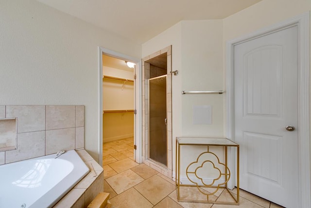 full bath featuring a garden tub, a shower stall, a walk in closet, and tile patterned floors