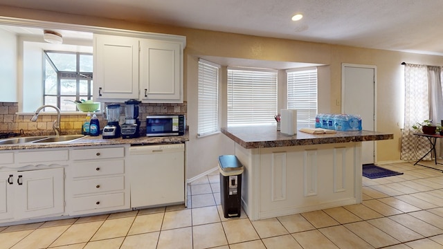 3806 Neely Ave, Midland, TX 79707 - kitchen with white dishwasher, stainless steel microwave, plenty of natural light, and decorative backsplash