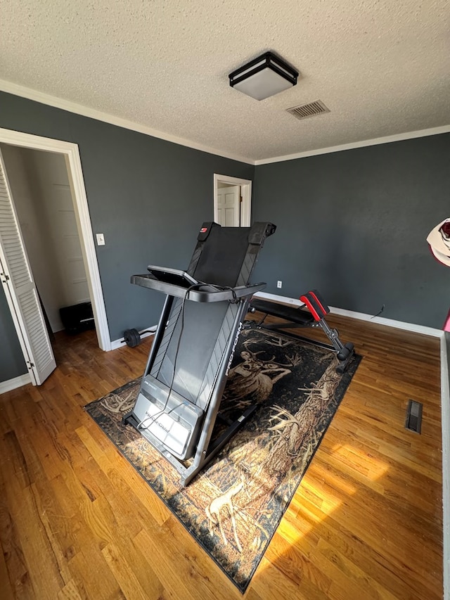 workout area with crown molding, a textured ceiling, and hardwood / wood-style flooring