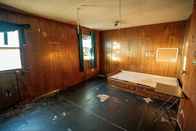 empty room featuring a textured ceiling and wooden walls