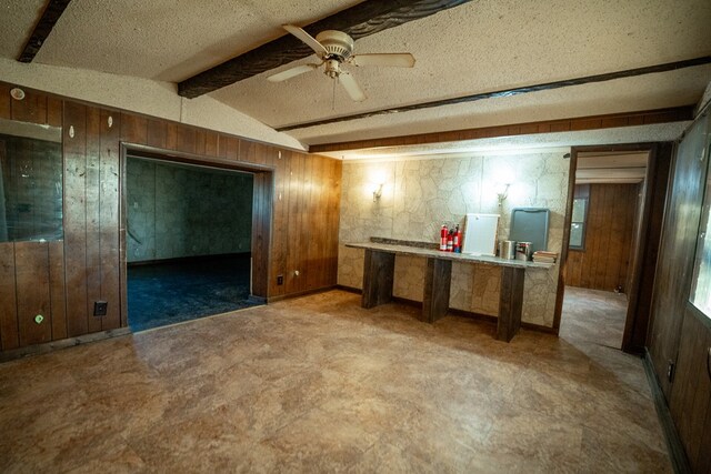 kitchen featuring wood walls, ceiling fan, lofted ceiling with beams, and a textured ceiling