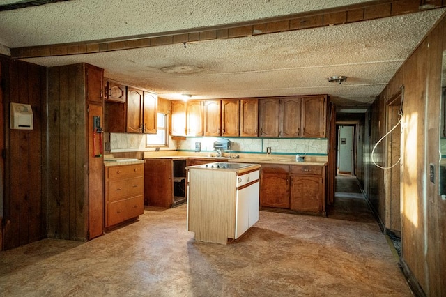 kitchen featuring wood walls, decorative backsplash, a kitchen island, and a textured ceiling