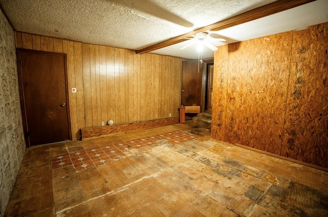 unfurnished room with ceiling fan, wood walls, and a textured ceiling