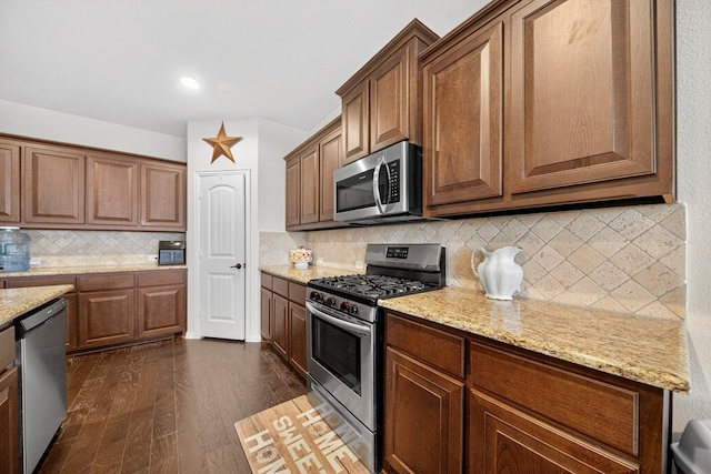 5001 Shadybrook Rd, Midland, TX 79705 - kitchen with stainless steel appliances, dark wood-style floors, tasteful backsplash, and light stone counters