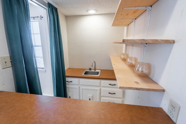 kitchen featuring a wealth of natural light, white cabinetry, a sink, and a textured ceiling