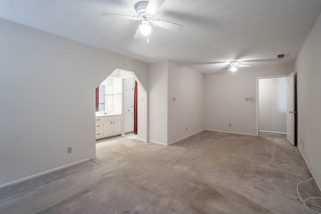 interior space featuring ceiling fan, a textured ceiling, baseboards, and light colored carpet