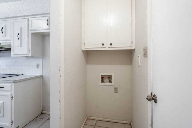 washroom with hookup for a washing machine, light tile patterned floors, and cabinet space