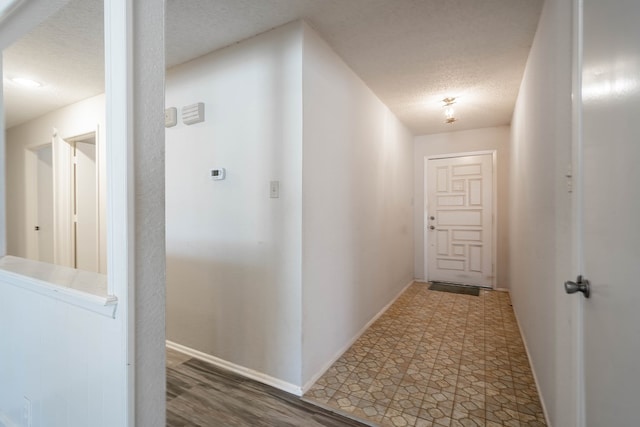 hallway with baseboards and a textured ceiling