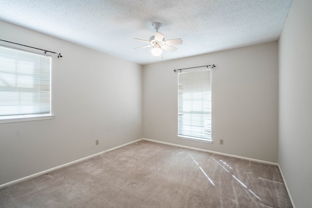 carpeted empty room featuring a textured ceiling, a ceiling fan, and baseboards