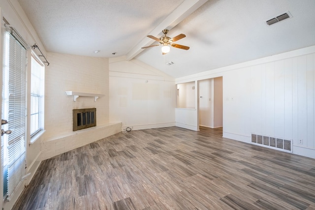 unfurnished living room with a textured ceiling, a fireplace, wood finished floors, and visible vents