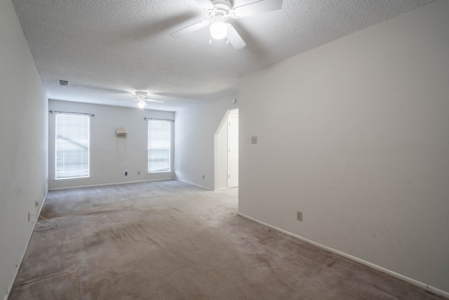 carpeted spare room with visible vents, ceiling fan, a textured ceiling, and baseboards