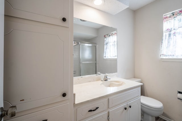 bathroom with a shower with shower door, vanity, and toilet