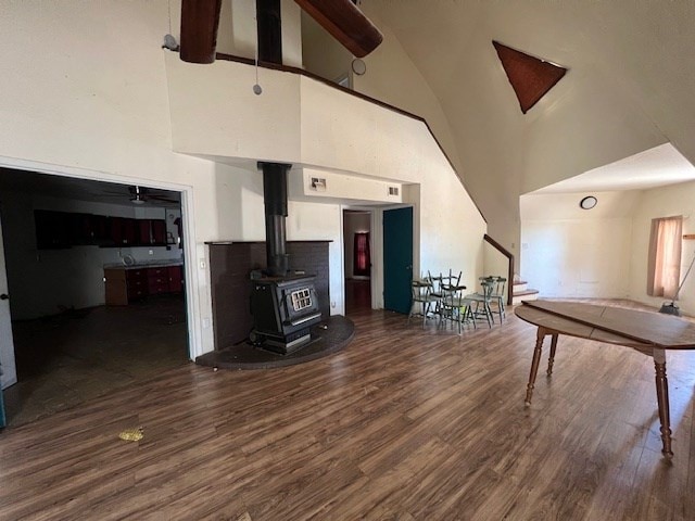 interior space with a wood stove, ceiling fan, dark hardwood / wood-style flooring, and high vaulted ceiling