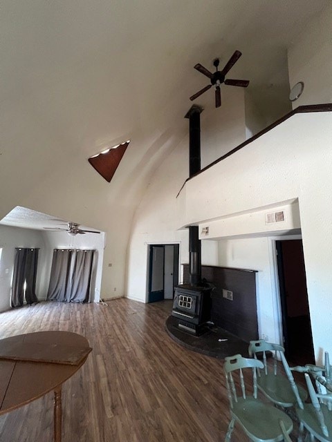 living room with a wood stove, ceiling fan, dark hardwood / wood-style flooring, and high vaulted ceiling