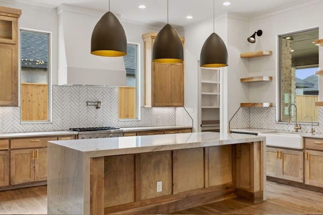 kitchen with backsplash, a center island, light hardwood / wood-style floors, and stainless steel gas cooktop