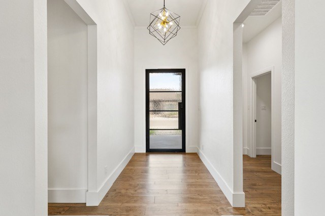 foyer with crown molding, a notable chandelier, and hardwood / wood-style flooring