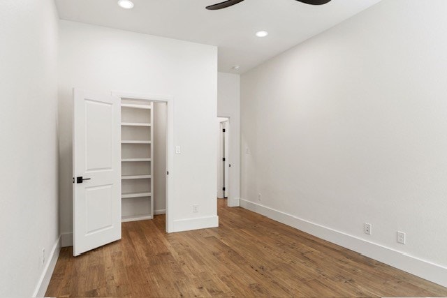 unfurnished bedroom featuring ceiling fan, wood-type flooring, and a spacious closet