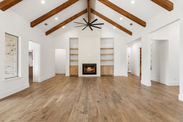 unfurnished living room featuring beam ceiling, light hardwood / wood-style flooring, and high vaulted ceiling