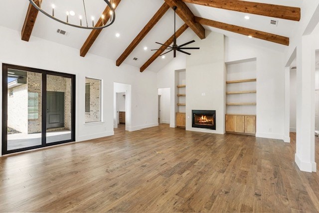 unfurnished living room with ceiling fan with notable chandelier, beam ceiling, wood-type flooring, and high vaulted ceiling