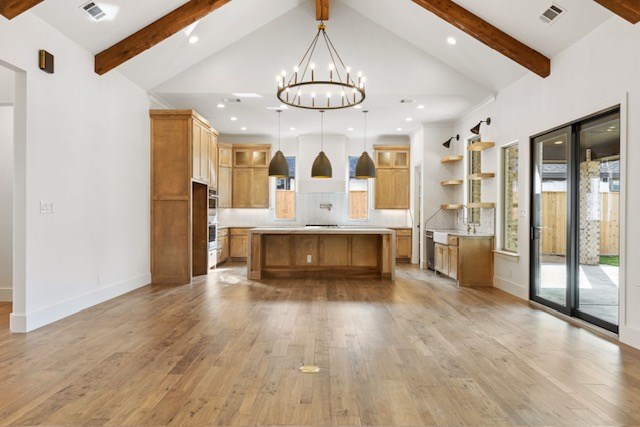 kitchen featuring decorative light fixtures, light hardwood / wood-style floors, a spacious island, and lofted ceiling with beams