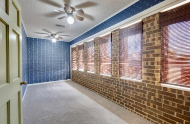 carpeted empty room with baseboards, ceiling fan, wallpapered walls, and a textured ceiling