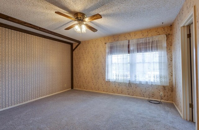 carpeted empty room featuring a ceiling fan, wallpapered walls, and a textured ceiling