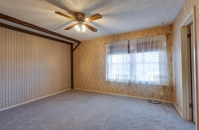 carpeted empty room featuring a ceiling fan, wallpapered walls, and a textured ceiling