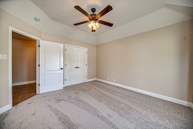 unfurnished bedroom with a raised ceiling, ceiling fan, and carpet flooring