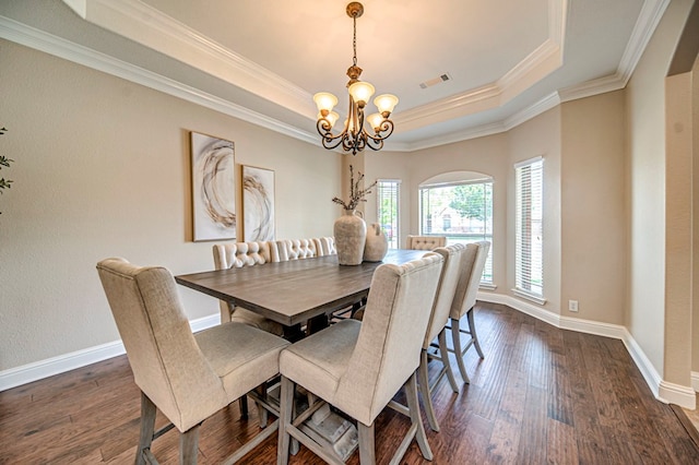 dining area with a raised ceiling, ornamental molding, a notable chandelier, and dark hardwood / wood-style floors